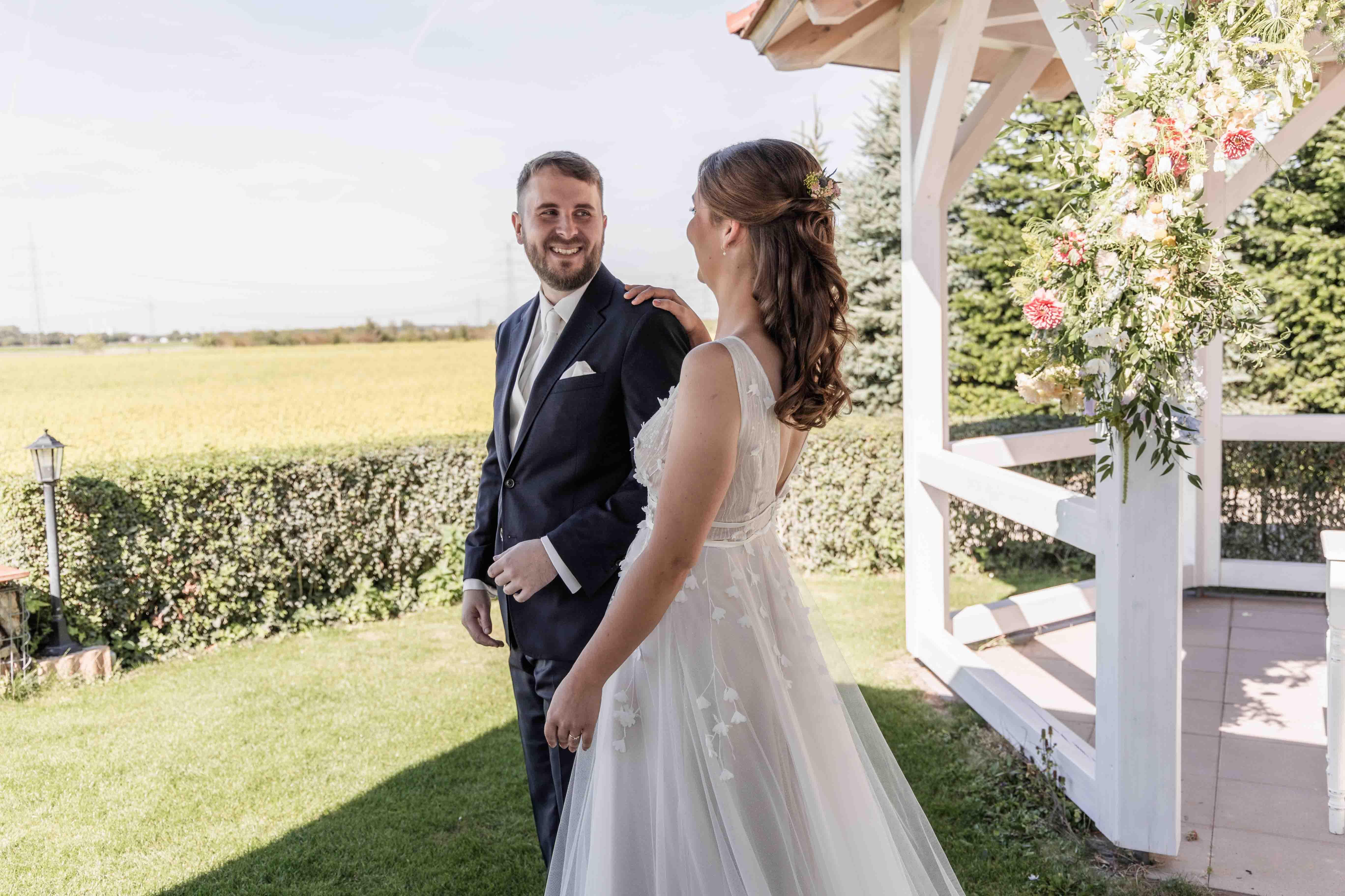 Hochzeitsfoto das Brautpaar schaut sich verliebt an neben dem Gazebo bei der freien Trauung