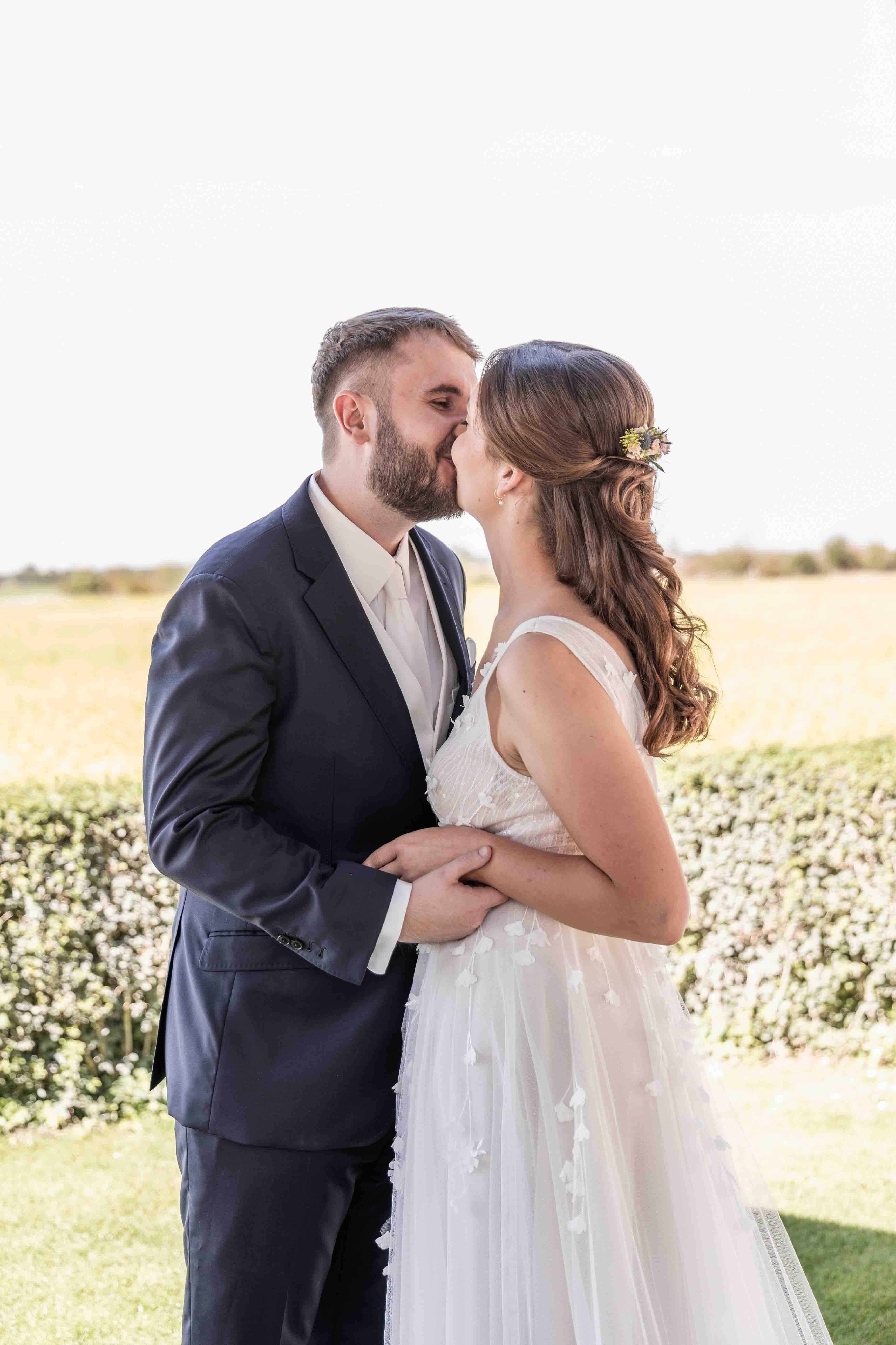 Hochzeitsfoto das Brautpaar küsst sich neben dem Gazebo bei der freien Trauung - Aufnahme von der Seite