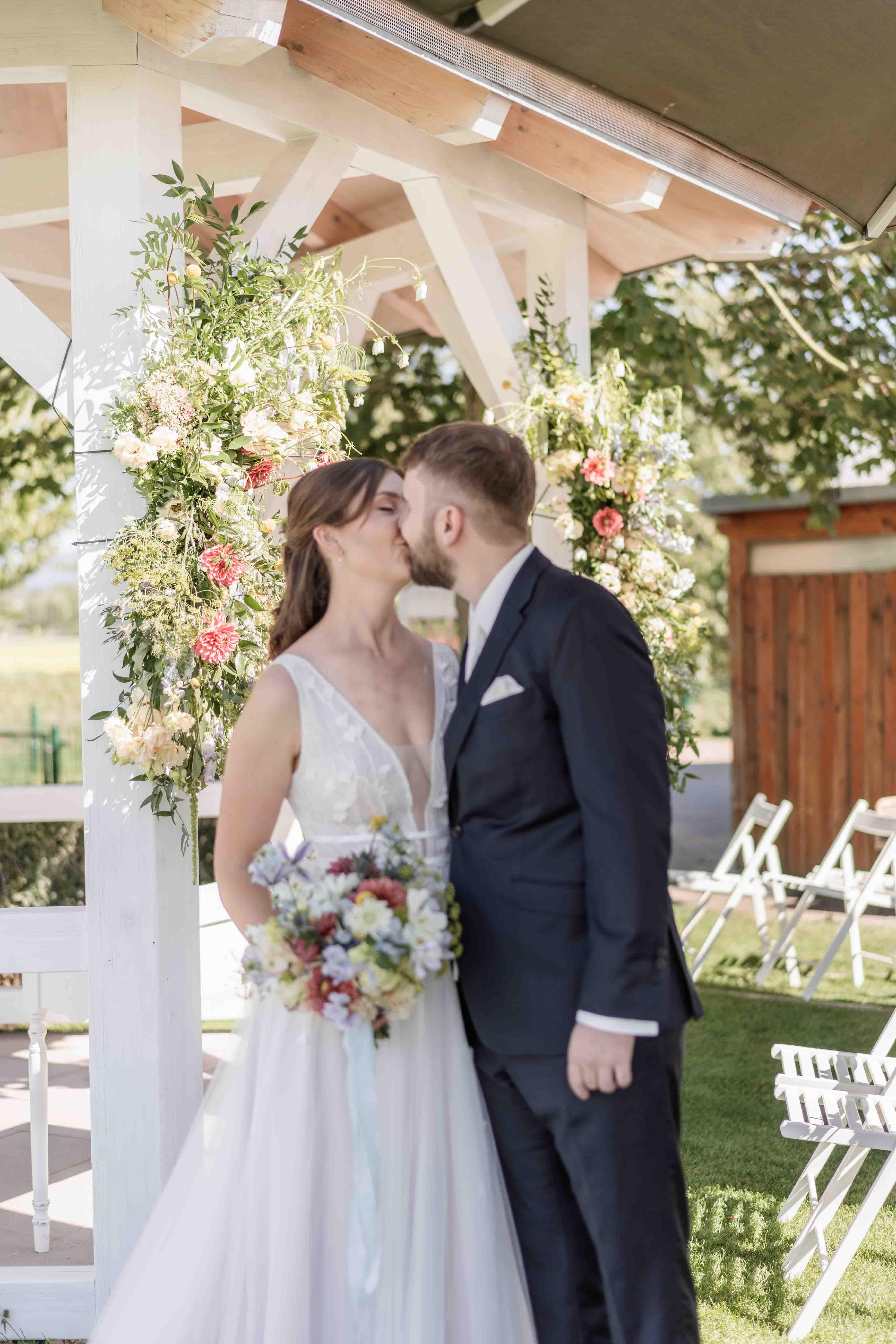 Hochzeitsfoto das Brautpaar küsst sich neben dem Gazebo bei der freien Trauung - Aufnahme von vorne