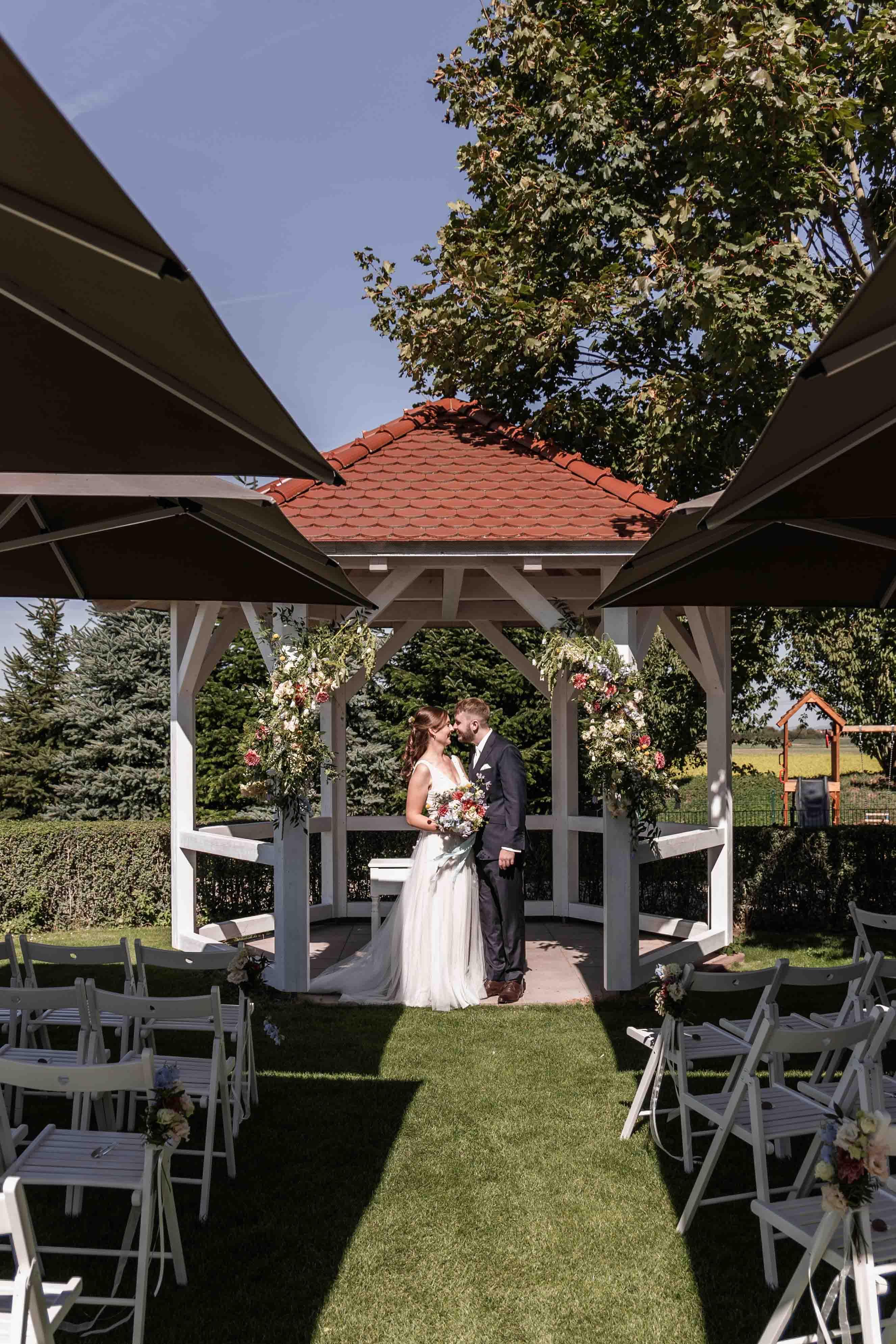 Hochzeitsfoto das Brautpaar küsst sich vor dem Gazebo bei der freien Trauung