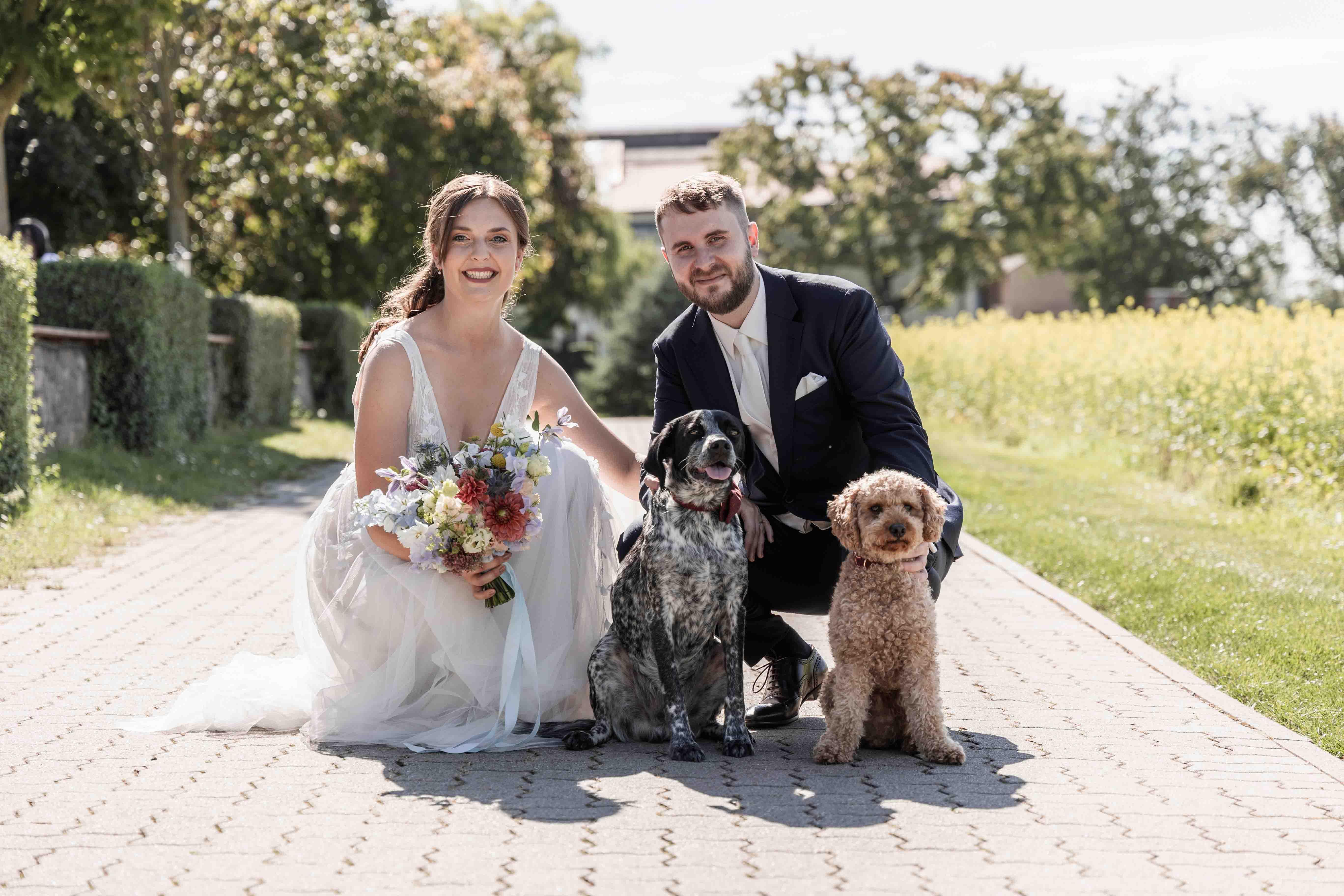 Hochzeitsfoto des Brautpaars kniend zusammen mit ihren Hunden