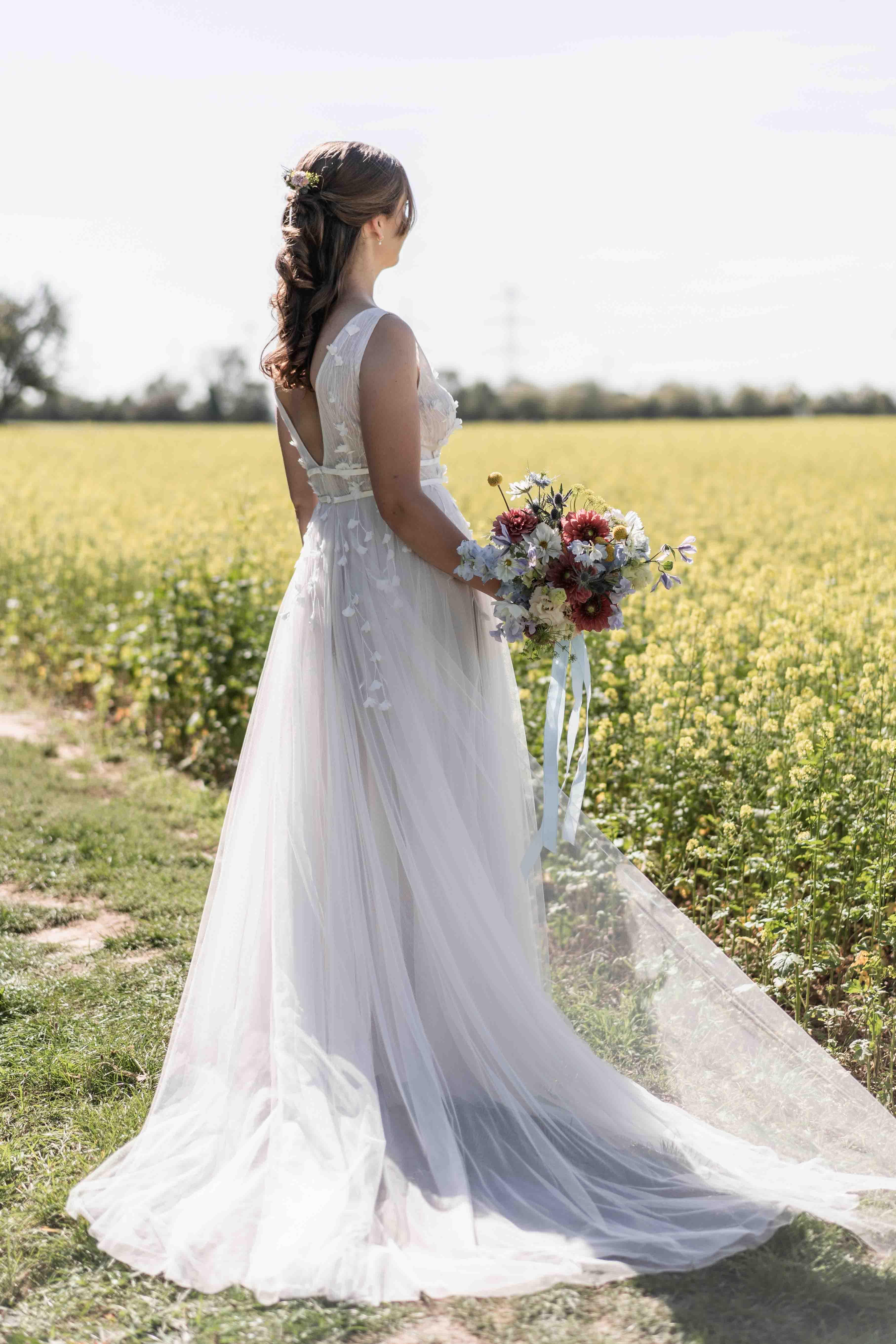 Hochzeitsfoto der Braut mit dem Brautstrauß, bei dem die Braut in die Ferne schaut