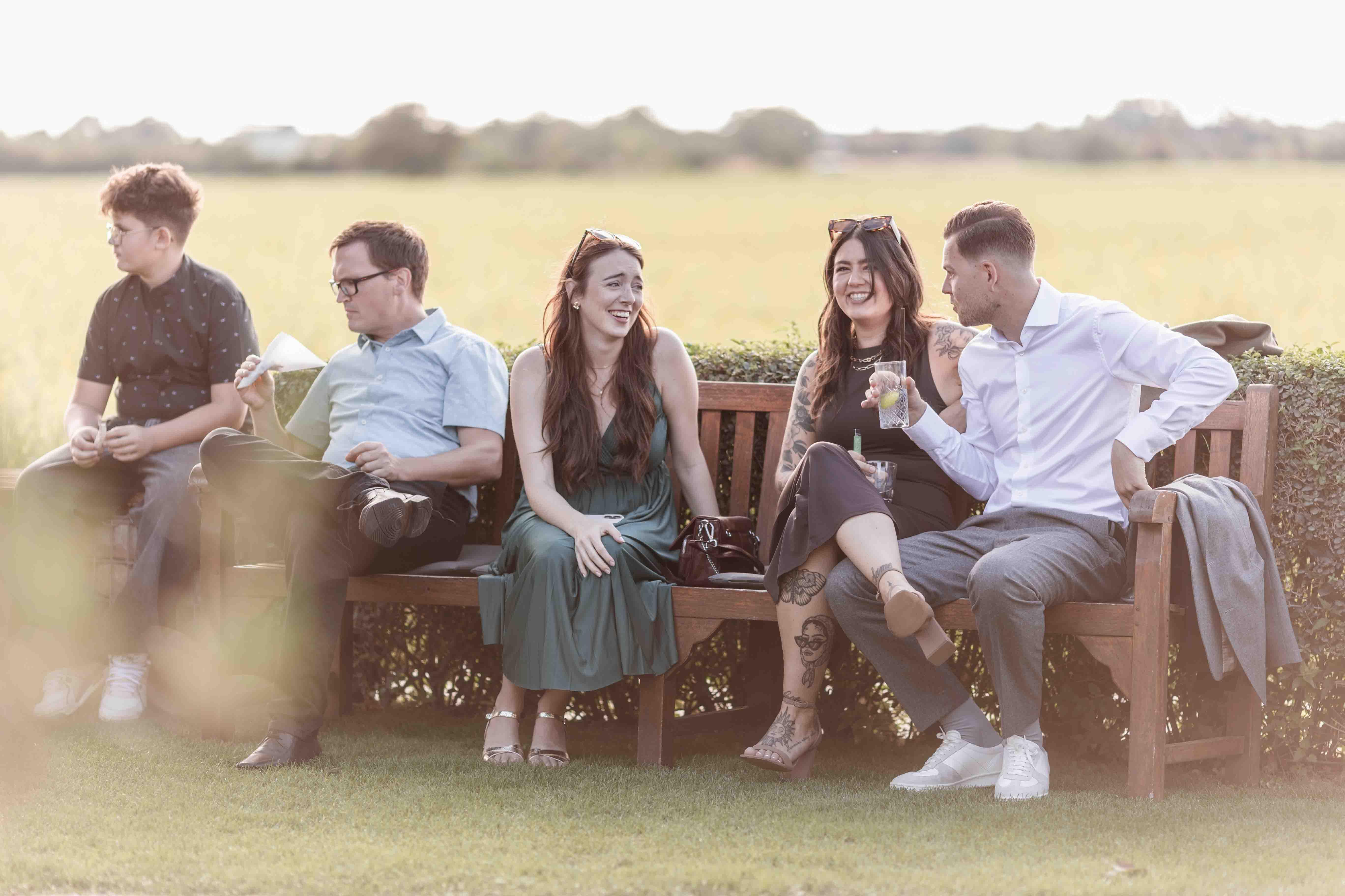 Hochzeitsfoto der Gäste auf einer Bank sitzend