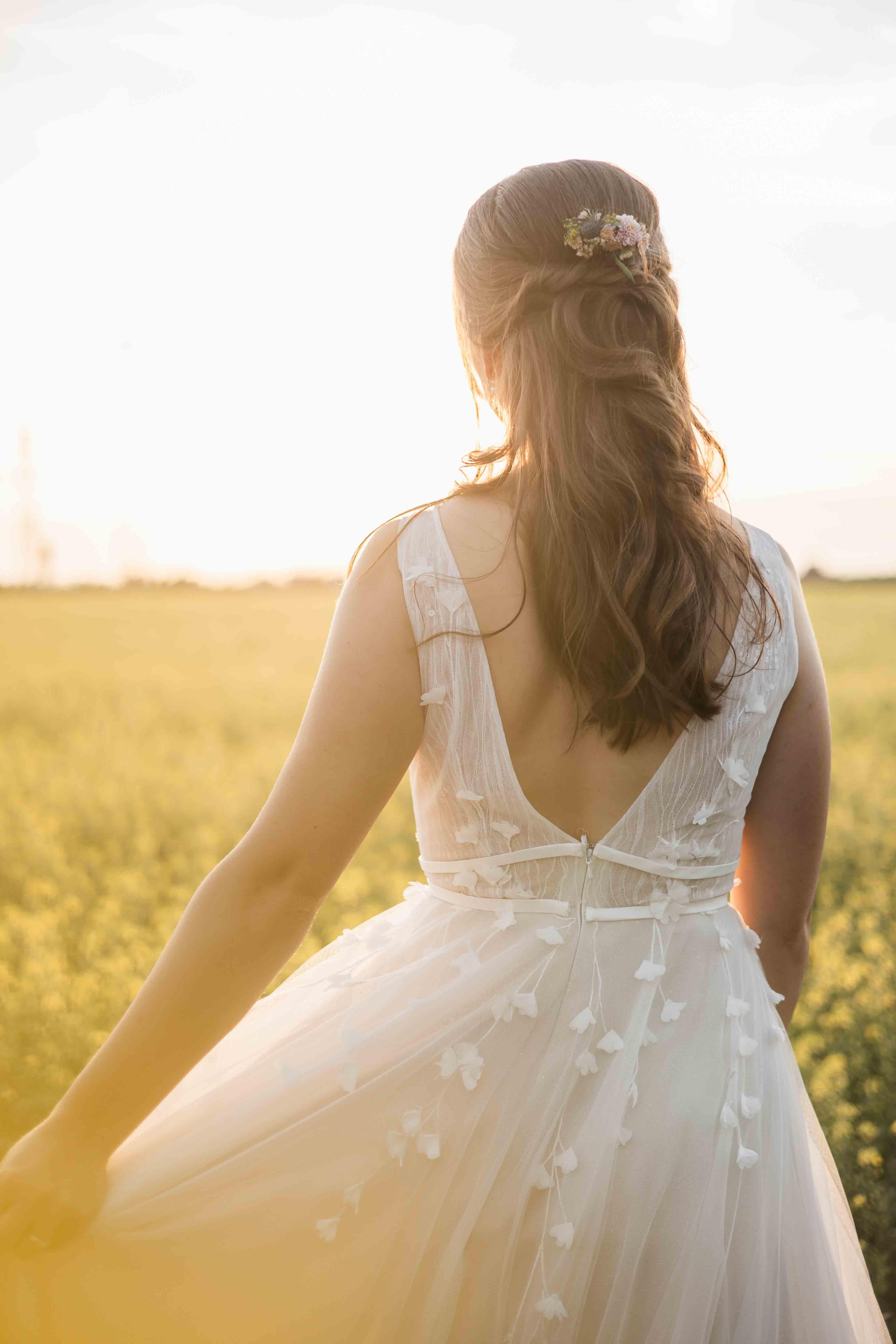 Hochzeitsfoto der Braut bei Sonnenuntergang vor dem Rapsfeld