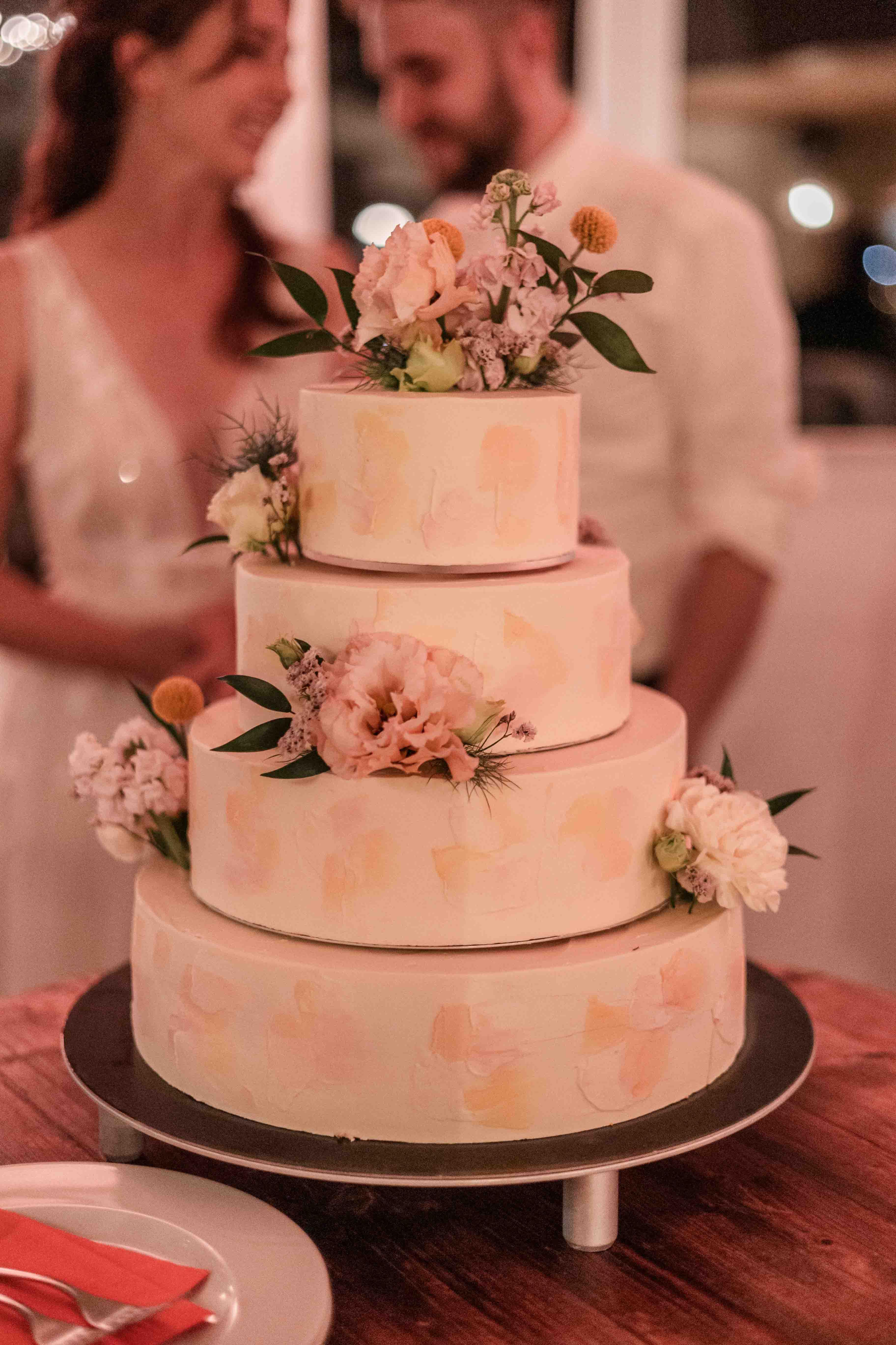 Hochzeitsfoto der Hochzeitstorte mit dem Brautpaar im Hintergrund unscharf