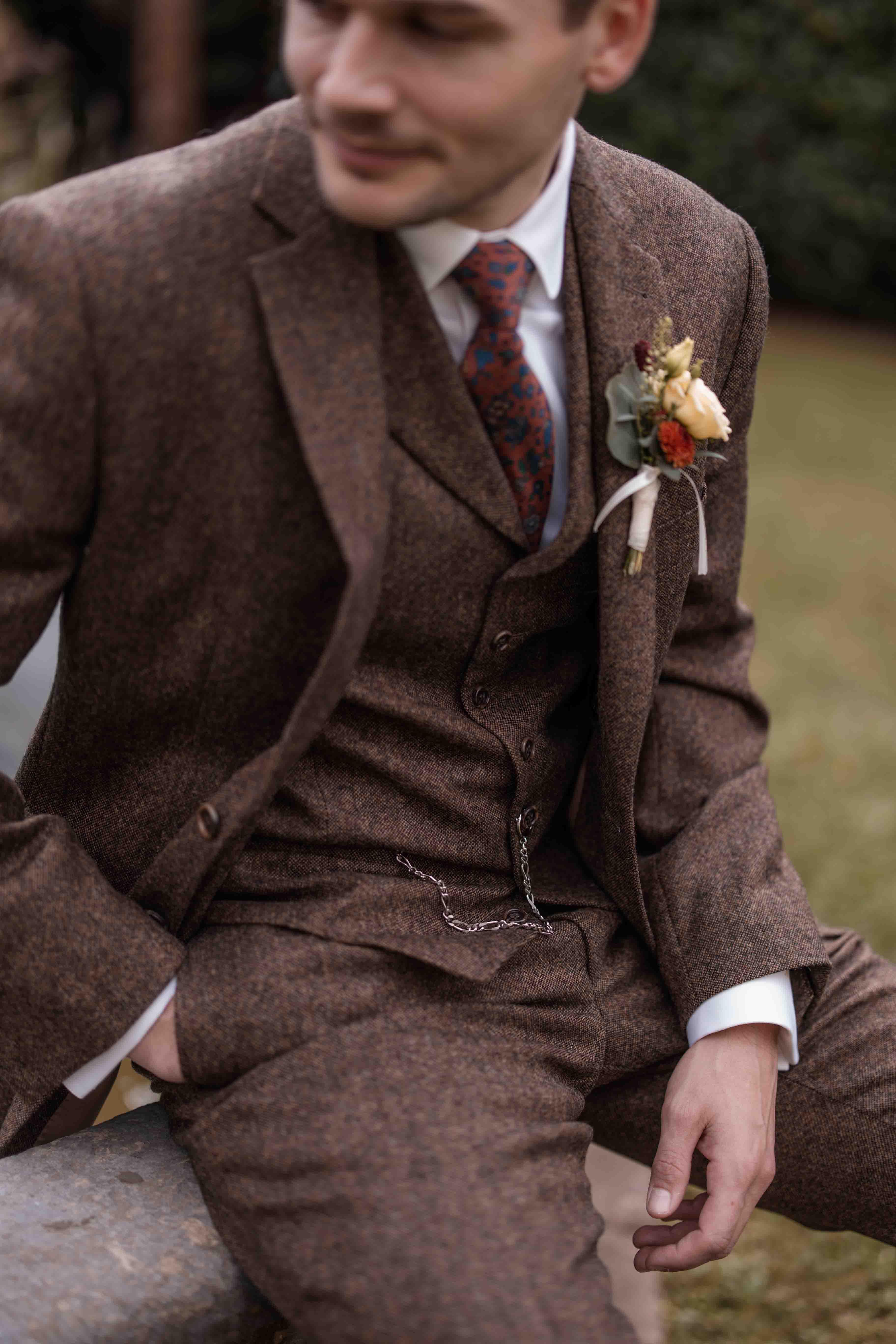 Hochzeitsfoto Nahaufnahme Bräutigam mit Jaquette und Blumenanstecker sitzend