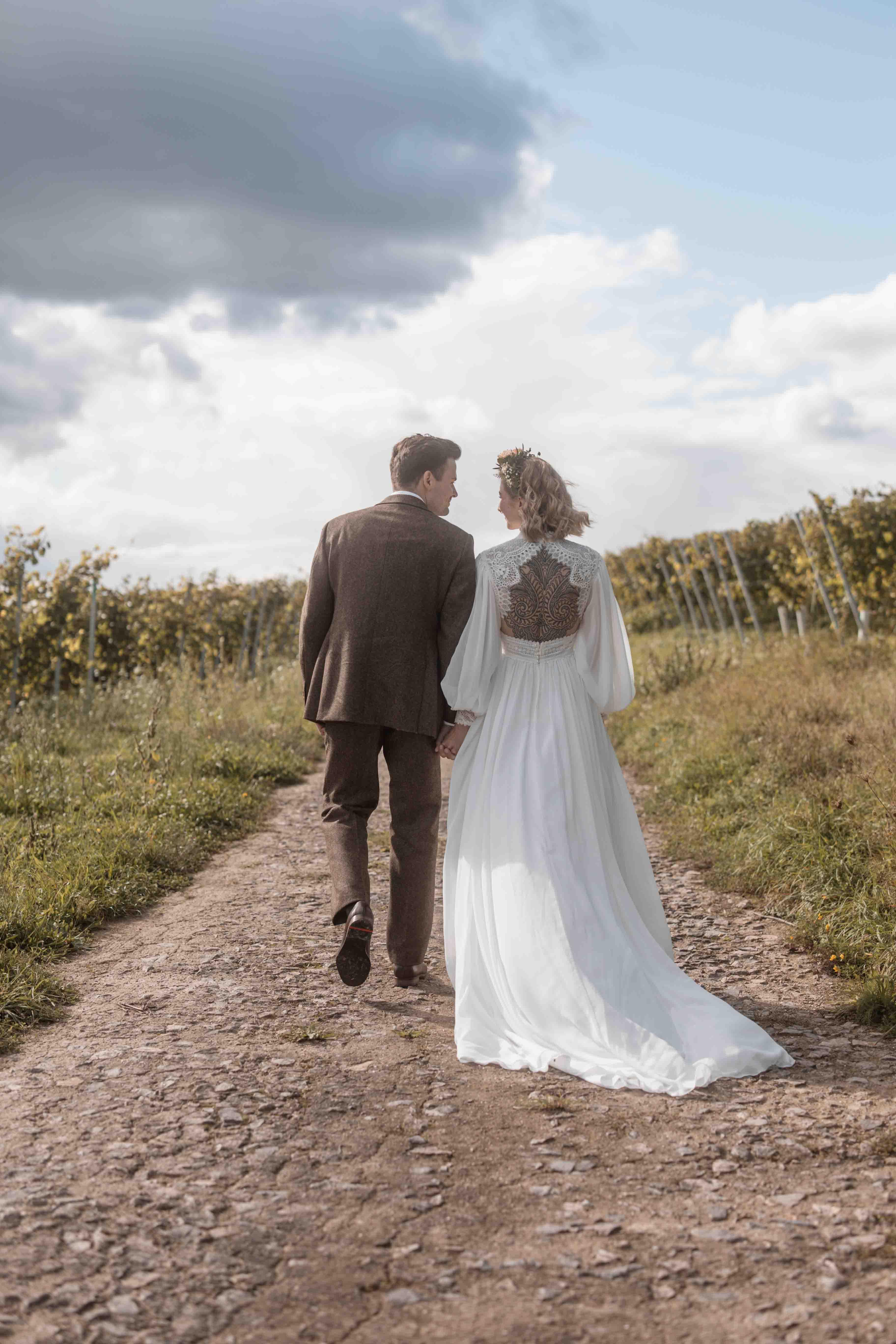 Hochzeitsfoto des Brautpaars zusammen auf einem Weg in die Ferne laufend