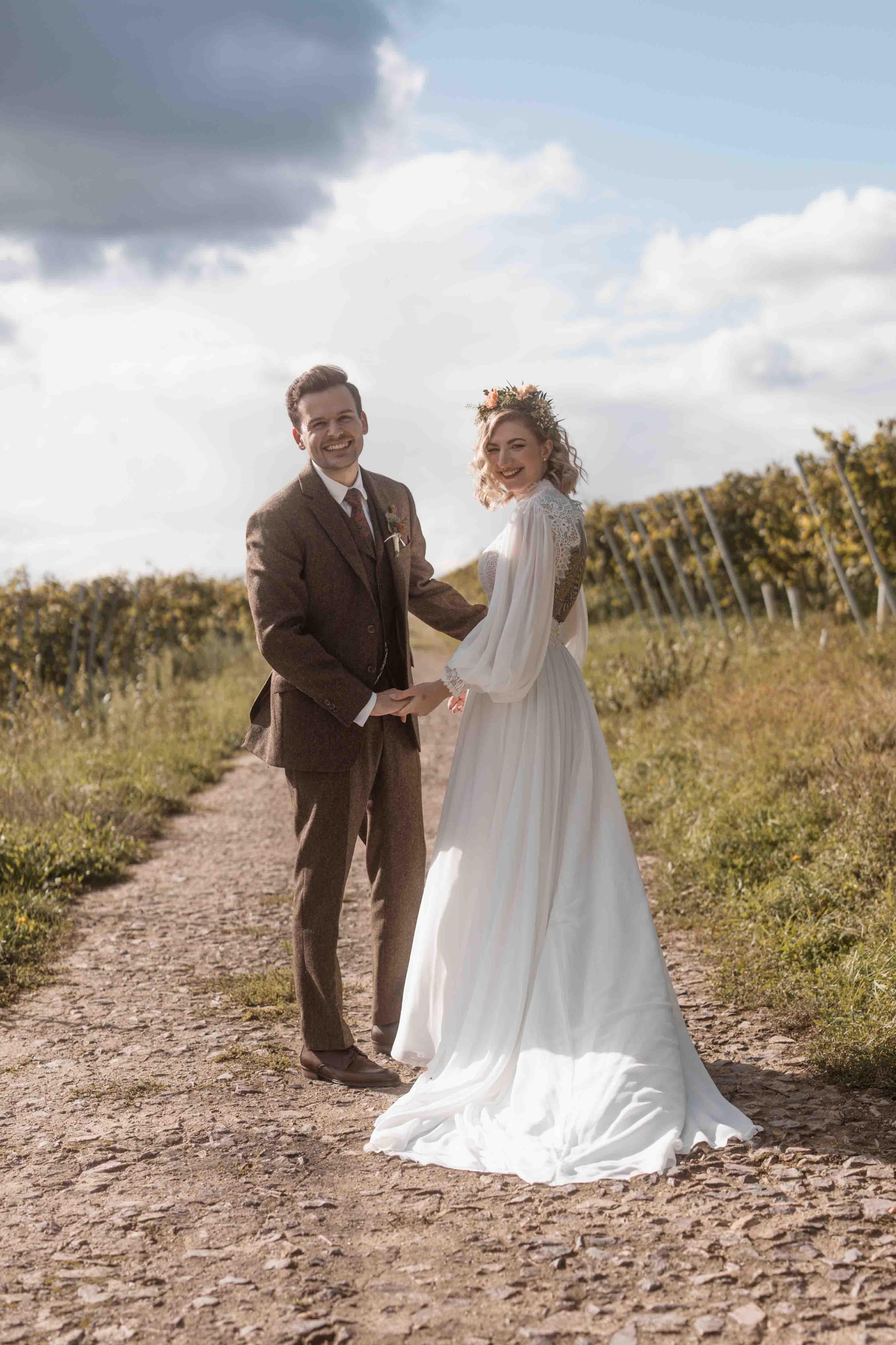 Hochzeitsfoto des Brautpaars zusammen auf einem Weg in die Kamera schauend
