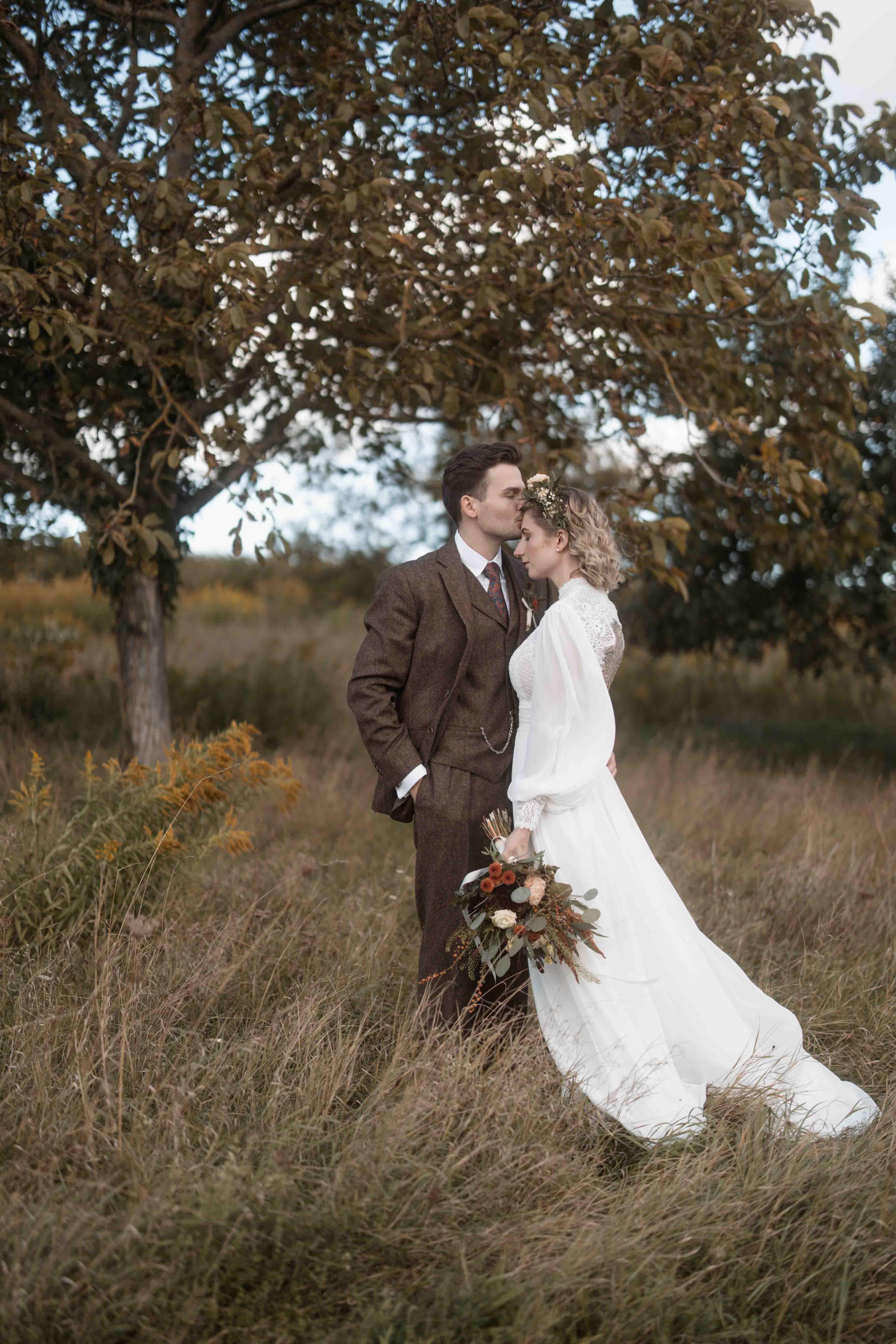 Hochzeitsfoto des Brautpaars auf einer Wiese küssend