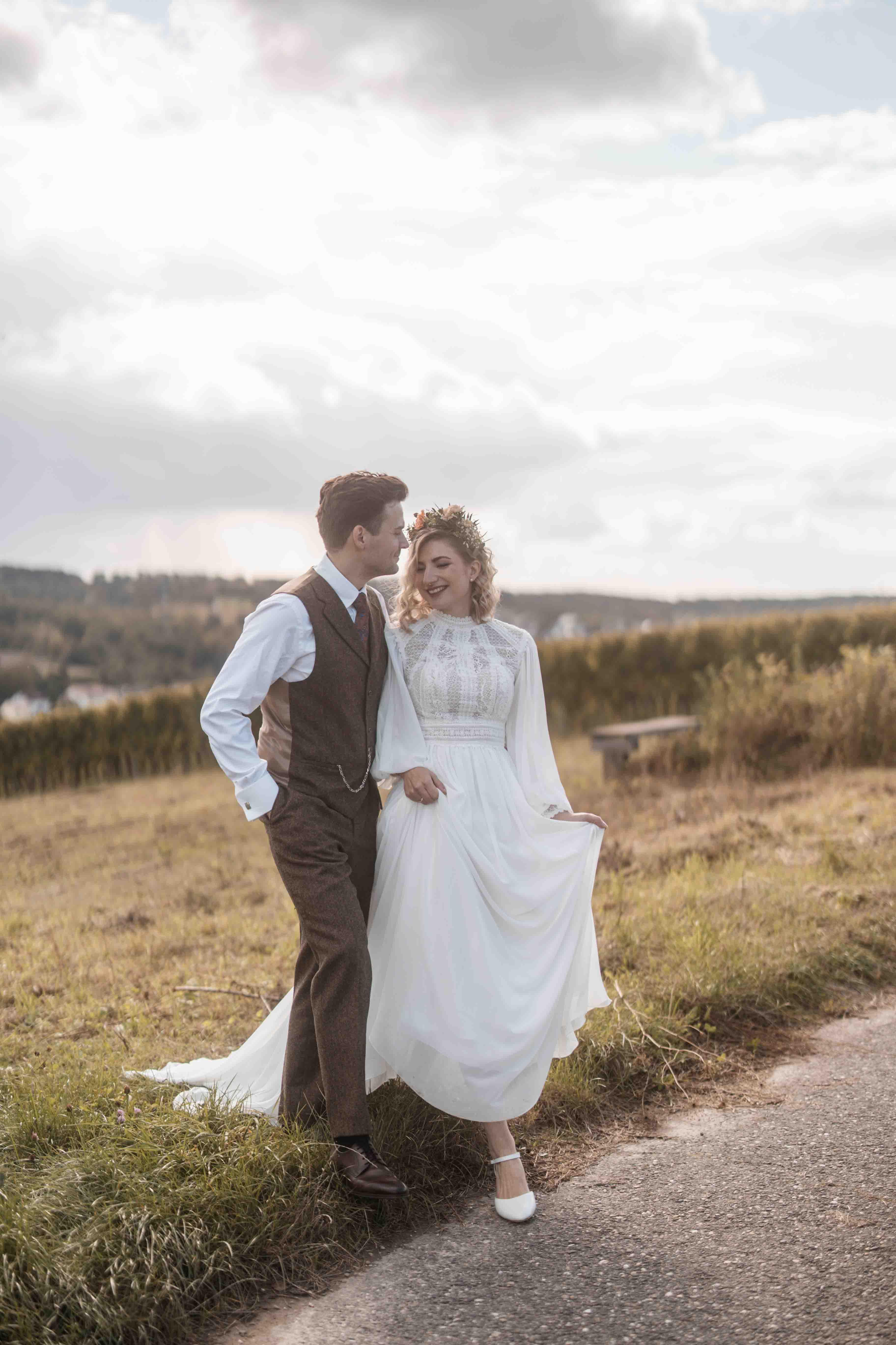 Hochzeitsfoto mit Brautpaar von der Wiese auf den Weg laufend