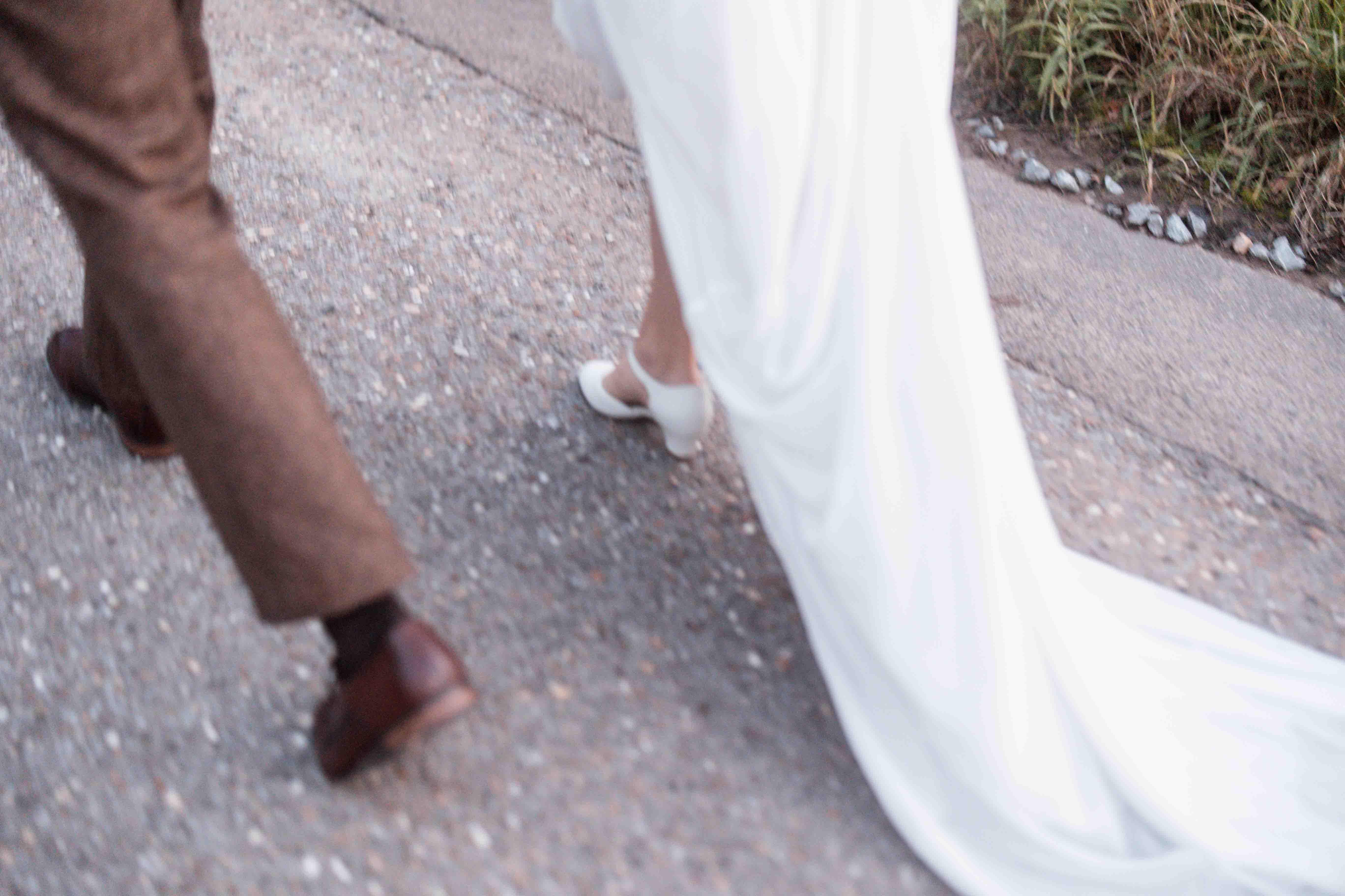 Hochzeitsfoto stilistisch unscharf mit den Beinen des Brautpaars beim Laufen auf einem Weg