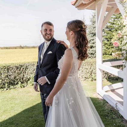 Hochzeitsfoto das Brautpaar schaut sich verliebt an neben dem Gazebo bei der freien Trauung