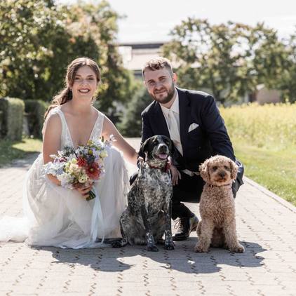 Hochzeitsfoto des Brautpaars kniend zusammen mit ihren Hunden