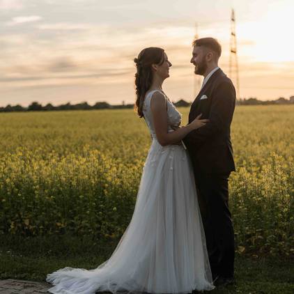 Hochzeitsfoto des Brautpaars bei Sonnenuntergang vor dem Rapsfeld