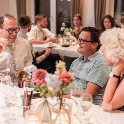 Hochzeitsfoto der Gäste in der Lokation an den Tischen sitzend