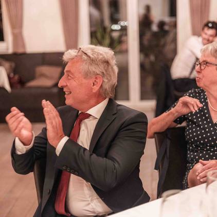 Hochzeitsfoto der Gäste in der Lokation an den Tischen sitzend - Das Abendprogramm ist gestartet und Gäste klatschen