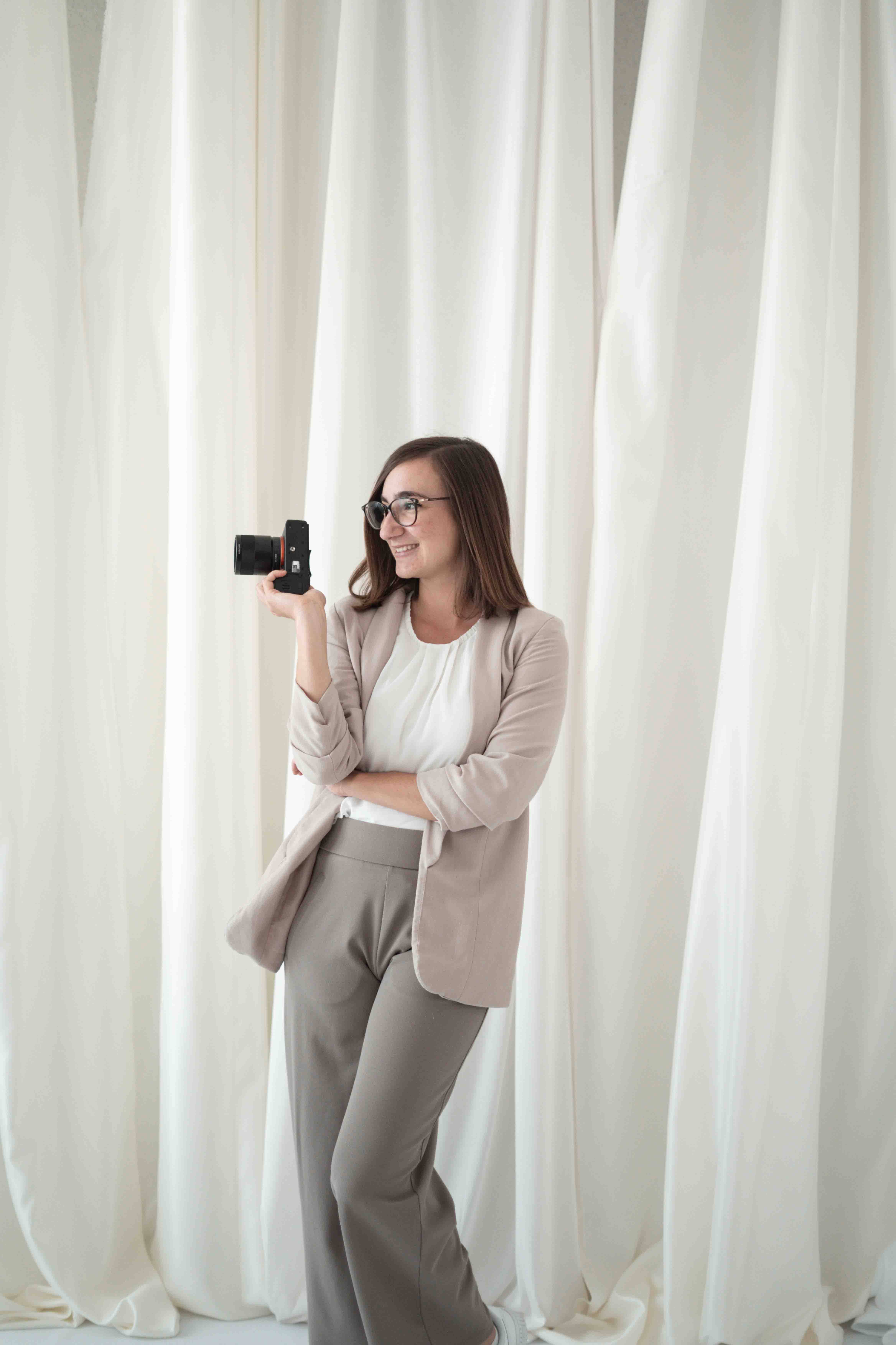Hochzeitsvideografin mit Kamera in der Hand seitlich fotografiert